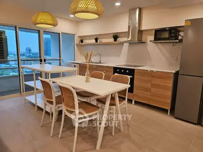 Modern kitchen with open layout and dining area, featuring stylish lighting and city view.