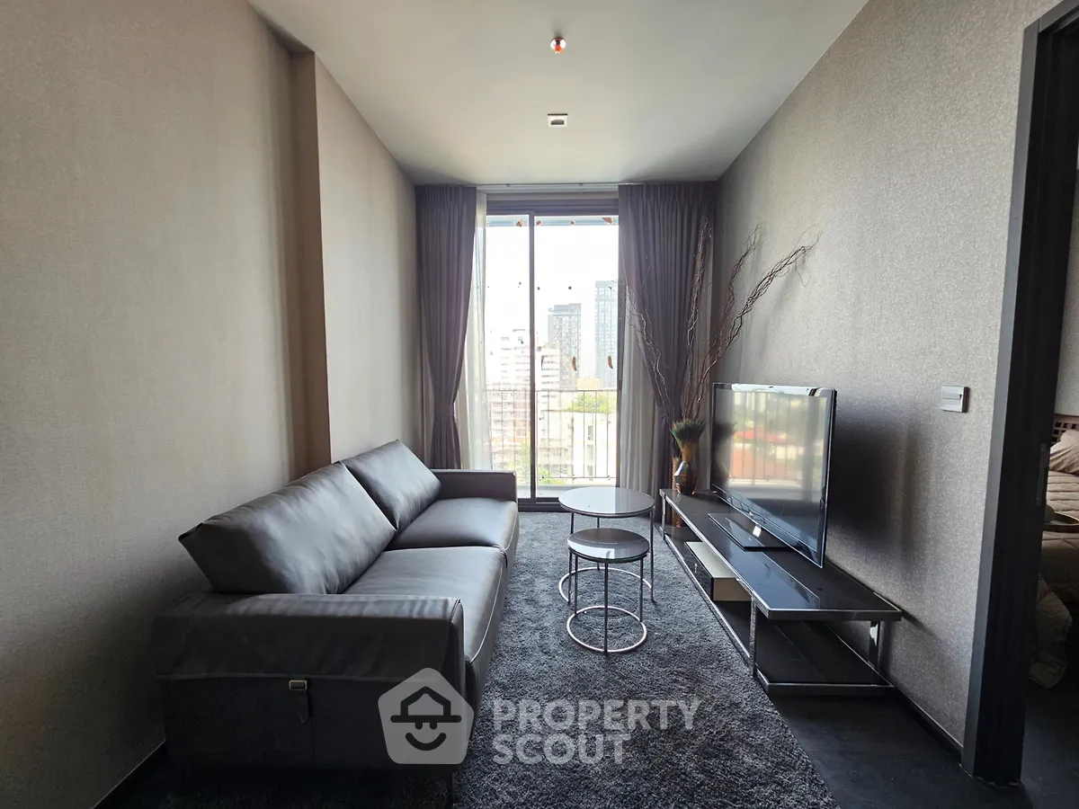 Modern living room with sleek furniture and city view from large window.