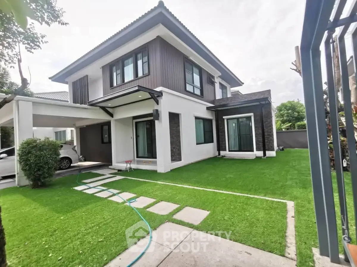 Modern two-story house with lush green lawn and carport in a serene neighborhood.