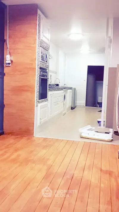 Modern kitchen with wooden flooring and built-in appliances, featuring a sleek design and ample space.