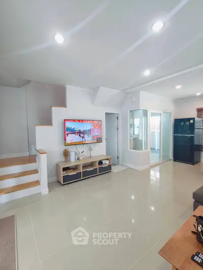 Modern living room with sleek design, featuring a staircase, TV, and glass shower enclosure.