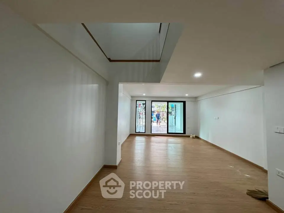 Spacious modern living room with wooden flooring and large windows for natural light.