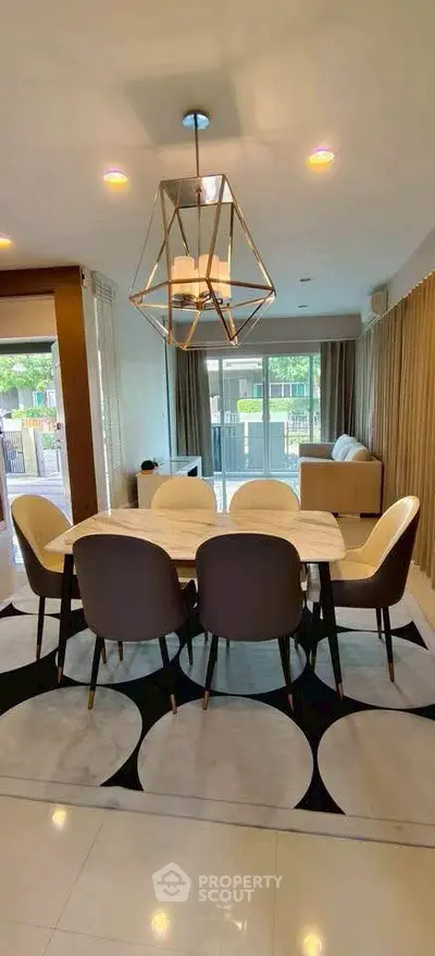 Elegant dining area with modern chandelier and large windows in a stylish open-plan living space.