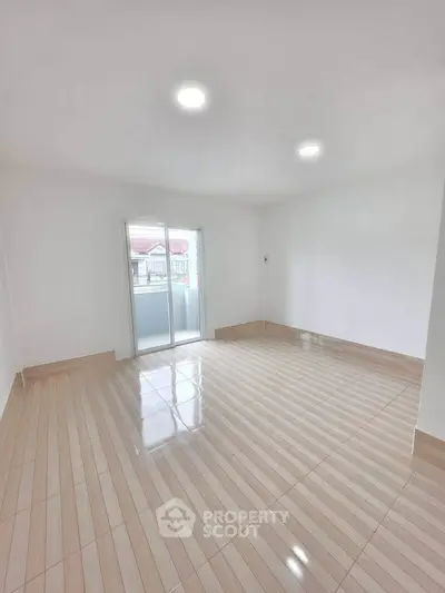 Spacious empty room with glossy tiled floor and balcony access, perfect for customization.