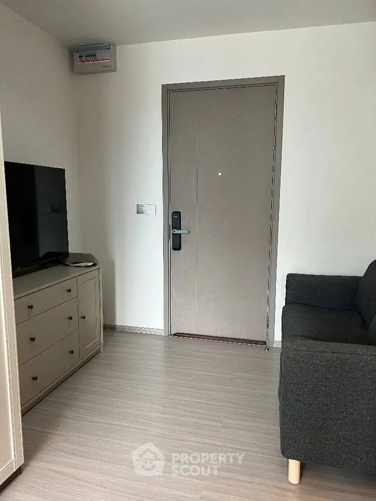 Cozy living room with modern sofa and TV unit, featuring a sleek entrance door.