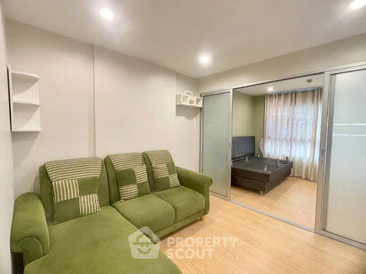 Modern living room with green sofa and sliding doors leading to bedroom