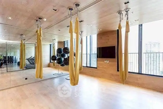 Luxurious gym with aerial yoga setup and floor-to-ceiling windows