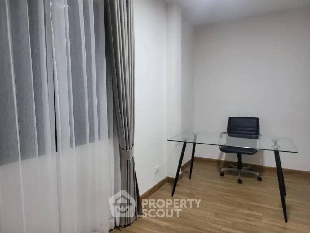 Modern minimalist study room with glass desk and sleek chair