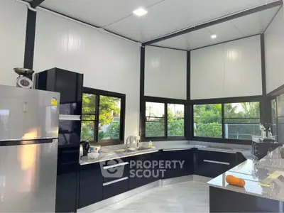 Modern kitchen with sleek black cabinets and large windows offering a scenic view.