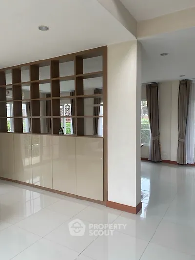 Spacious modern living area with sleek built-in shelving and large windows.
