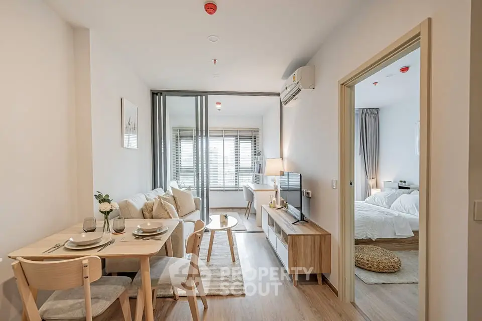 Modern open-plan living room and bedroom in a stylish apartment with natural light and cozy decor.