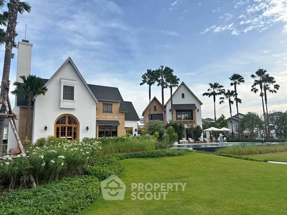 Charming modern houses with lush garden and palm trees under a clear blue sky.