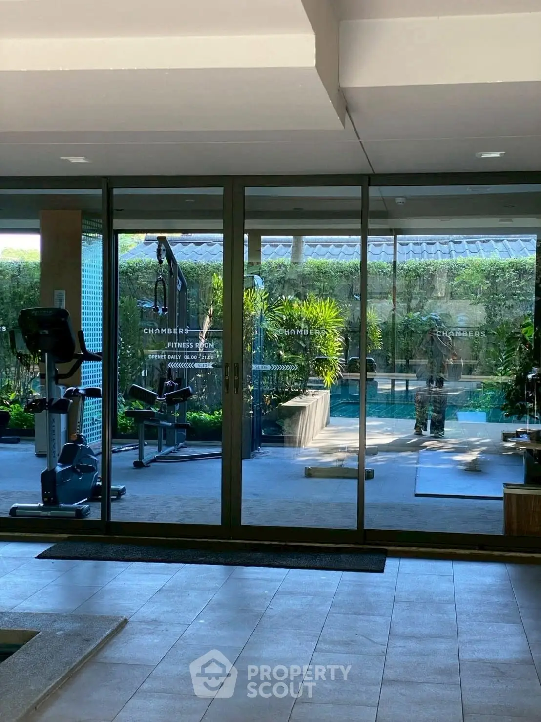 Modern fitness room with gym equipment and pool view in luxury property.