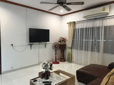 Spacious living room with modern decor, featuring a ceiling fan, wall-mounted TV, and comfortable seating.