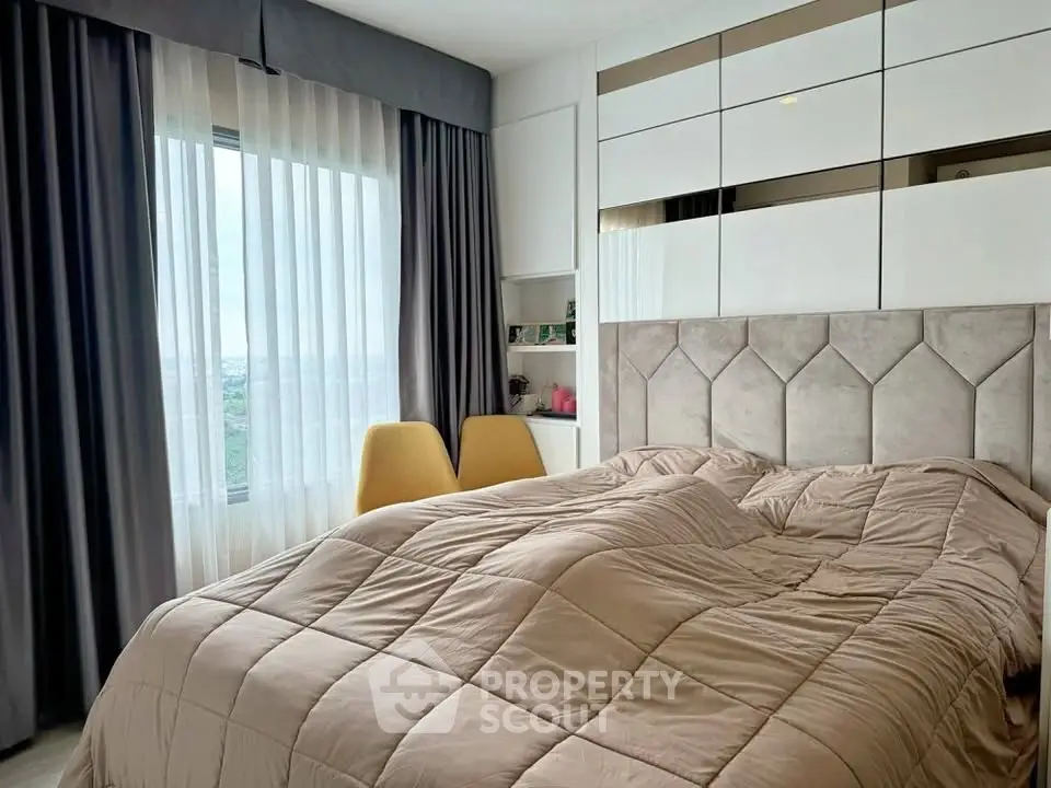 Modern bedroom with stylish decor and large window offering natural light.