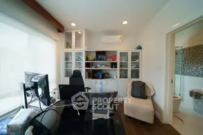 Modern home office with sleek desk, ergonomic chair, and built-in shelving, adjacent to a stylish bathroom.