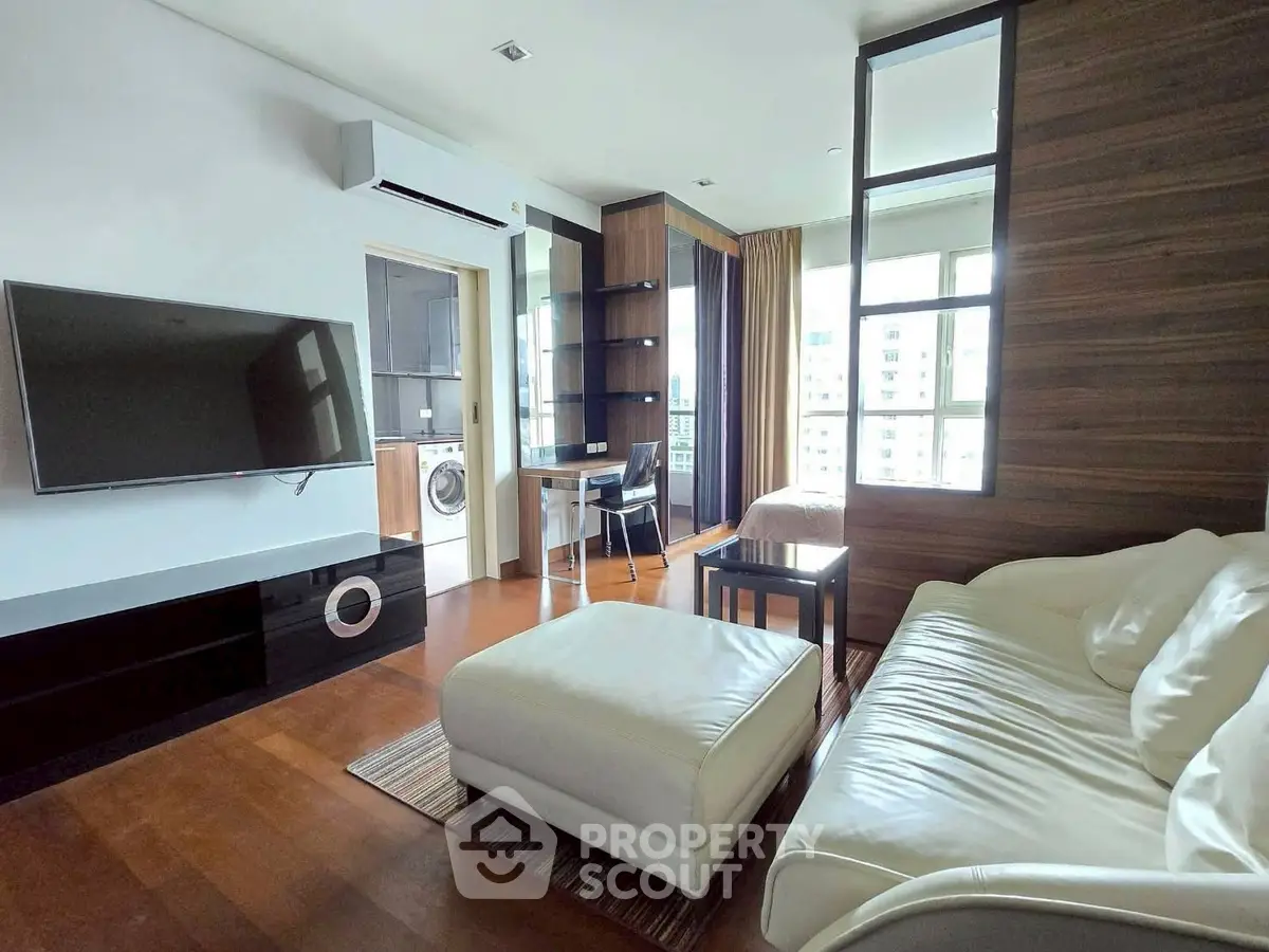 Modern living room with sleek furniture and large windows offering city views.