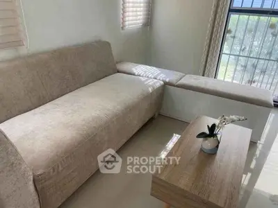Cozy living room with beige sofa and wooden coffee table near window.