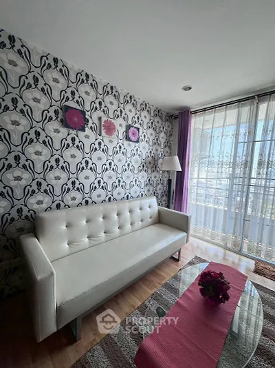 Chic living room with floral wallpaper and modern white sofa, featuring a glass coffee table and balcony view.