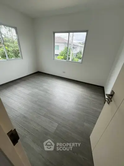 Spacious empty room with large windows and modern flooring, perfect for customization.
