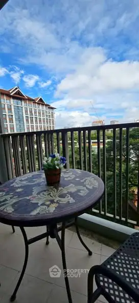 Charming balcony with floral table and scenic view of city skyline.