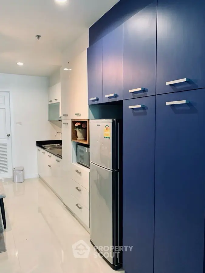 Modern kitchen with sleek blue cabinets and stainless steel appliances in a stylish apartment.