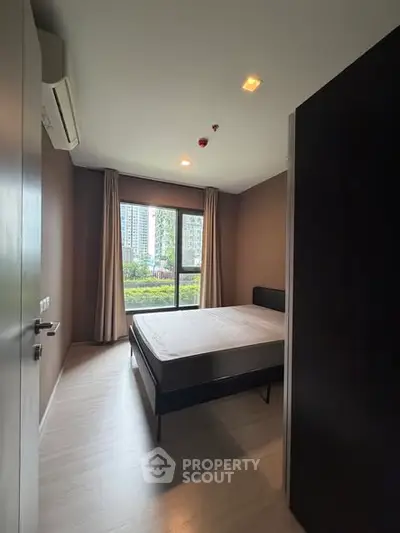 Modern bedroom with large window and city view, featuring minimalist design and natural light.