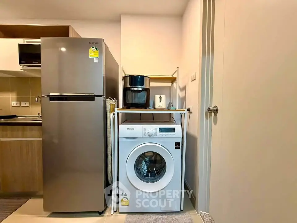 Modern kitchen with stainless steel fridge and washing machine in compact layout.