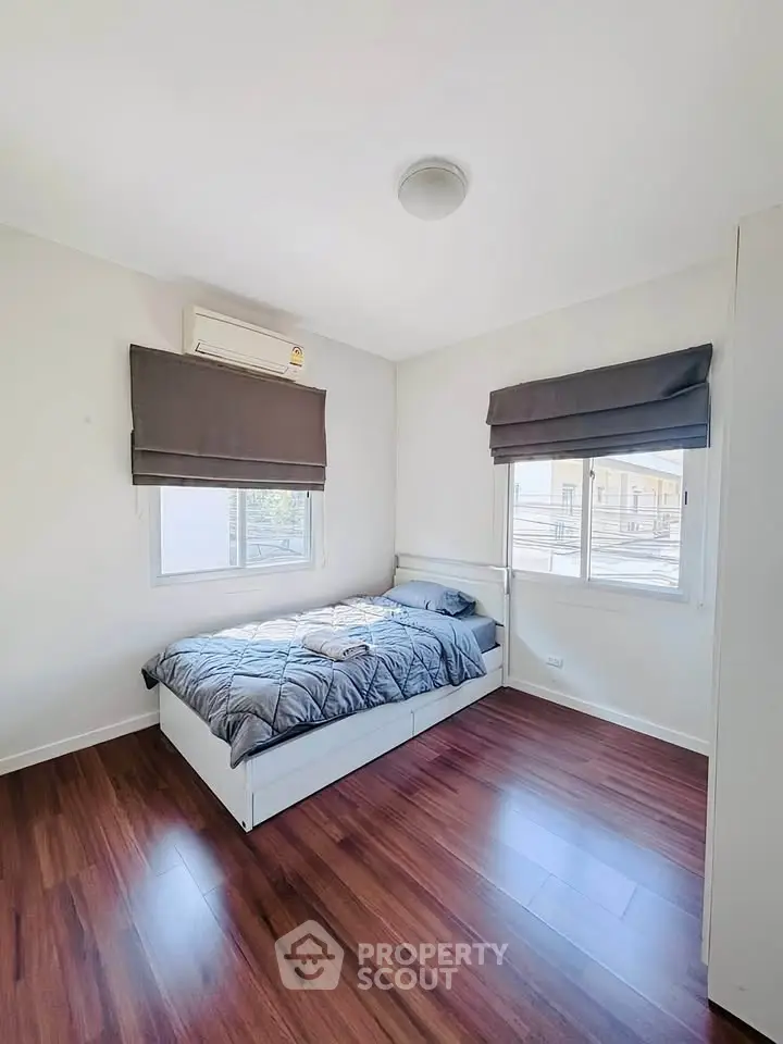 Bright bedroom with wooden flooring and large windows in modern apartment