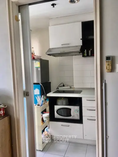 Compact kitchen with modern appliances and sleek cabinetry in a cozy apartment setting.