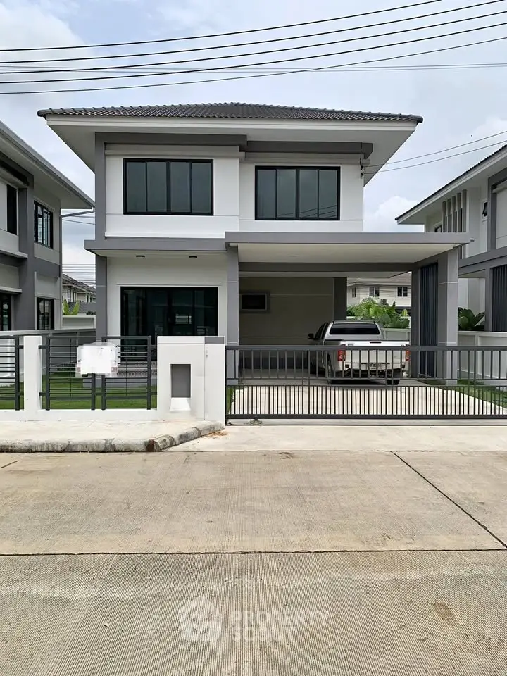 Modern two-story house with driveway and parked car in suburban neighborhood.