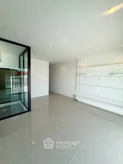 Spacious modern living room with sleek tile flooring and built-in shelving.