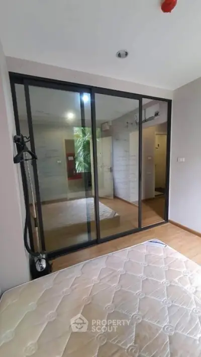 Modern bedroom with glass sliding doors and wooden flooring, offering a sleek and contemporary design.