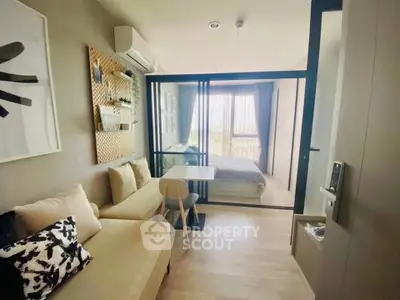 Modern studio apartment with cozy living area and stylish bedroom separated by glass partition.