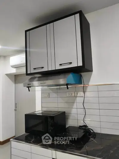 Modern kitchen with sleek cabinets and appliances, featuring a microwave and induction cooktop.
