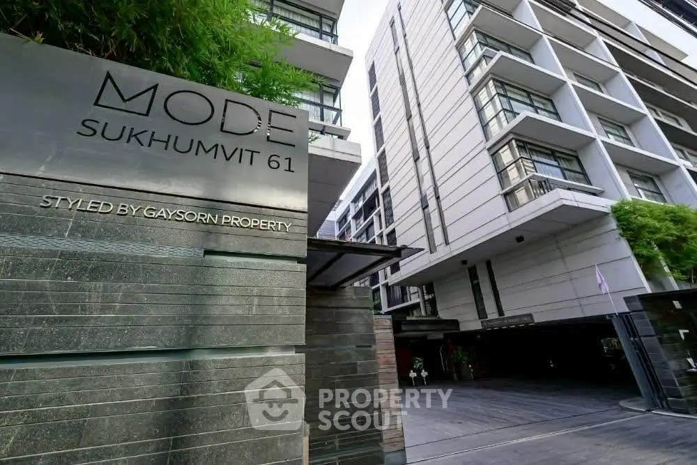 Modern condominium building exterior at Mode Sukhumvit 61 with stylish architecture and lush greenery.
