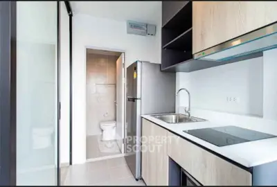 Modern compact kitchen with sleek appliances and adjacent bathroom view.