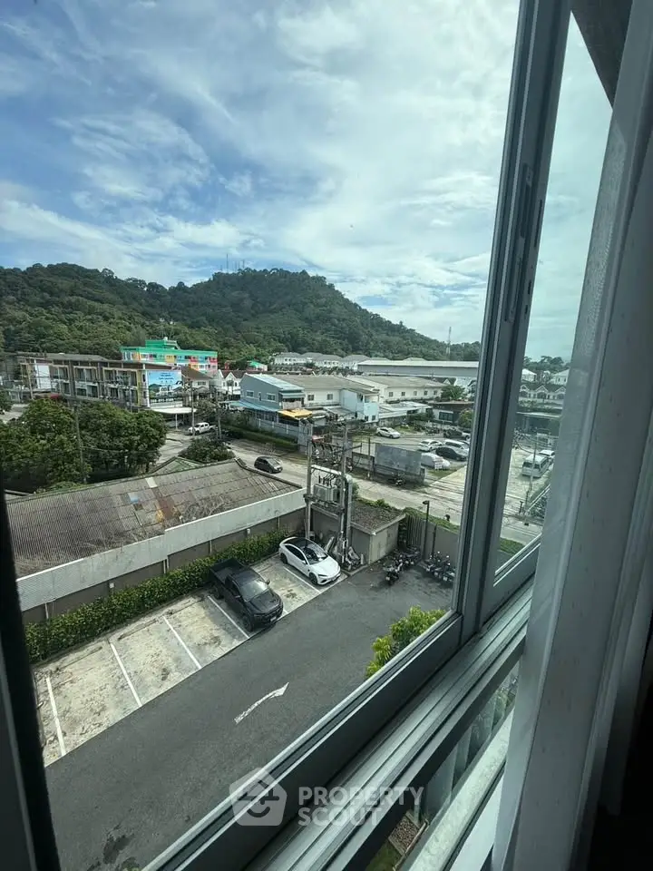 Scenic view from window overlooking parking area and lush green hills.
