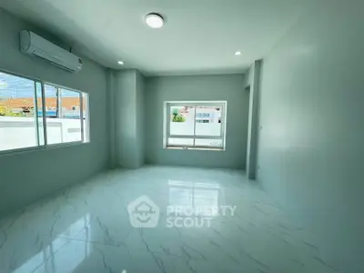 Spacious and bright living room with large windows and modern air conditioning unit.