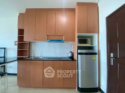 Modern kitchen with sleek wooden cabinets and stainless steel appliances in a cozy apartment.
