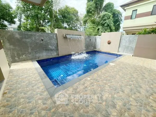 Luxurious private pool with waterfall feature in a serene backyard setting.