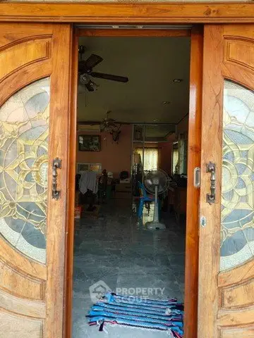 Inviting entrance with wooden doors leading to a cozy interior space, featuring a ceiling fan and decorative rug.