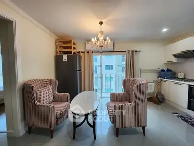 Charming living room with elegant chandelier and modern kitchen in open layout apartment.