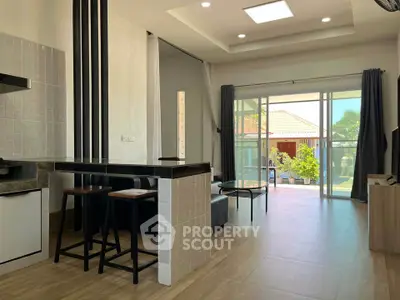 Modern open-plan living room with sleek kitchen and large sliding doors to garden view.