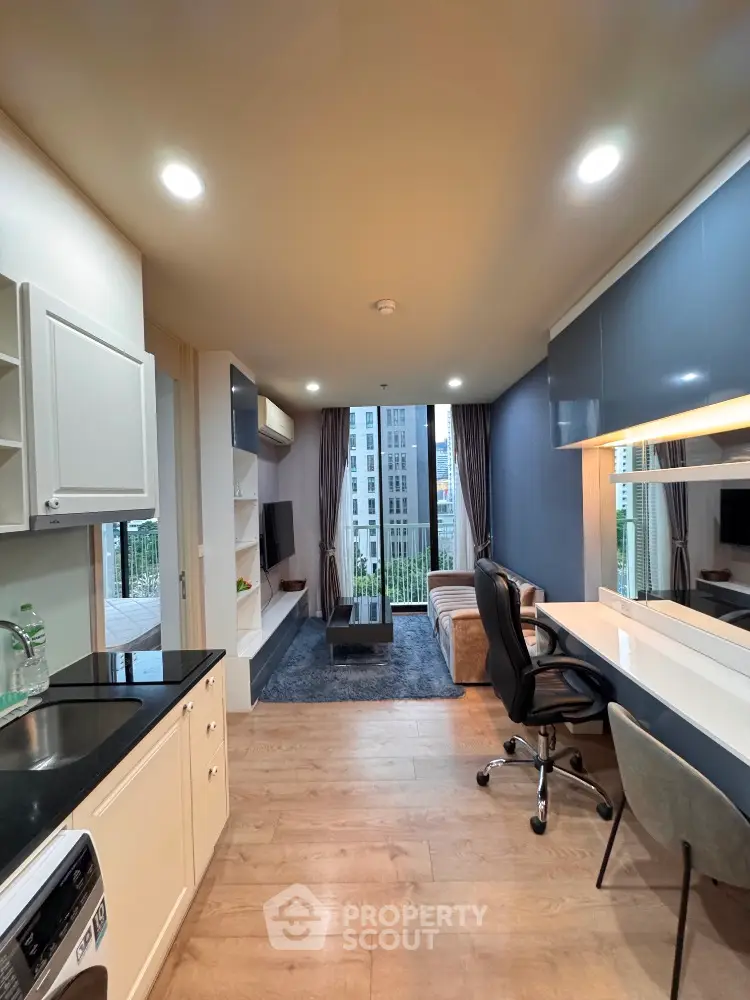 Modern apartment interior with open layout, featuring sleek kitchen and cozy living area with city view.