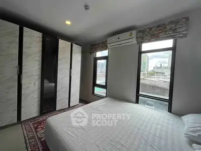 Modern bedroom with large windows and built-in wardrobe in urban apartment