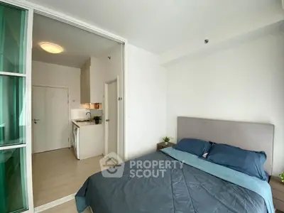 Modern bedroom with sliding glass doors and compact kitchen in a cozy apartment.