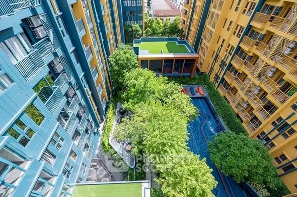 Stunning aerial view of modern apartment complex with lush greenery and inviting pool area.