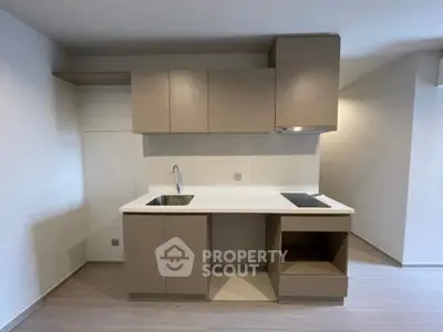 Modern minimalist kitchen with sleek cabinetry and built-in stovetop in a contemporary apartment.
