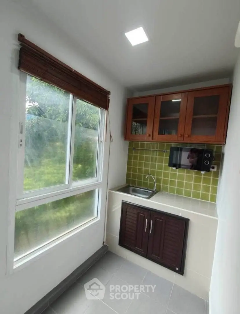 Compact kitchen with green tile backsplash and wooden cabinets